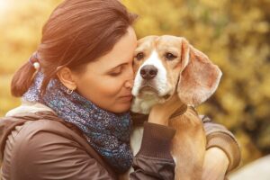 A dog owner hugs her pet emotionally, foreshadowing pet owners grieving pet loss.